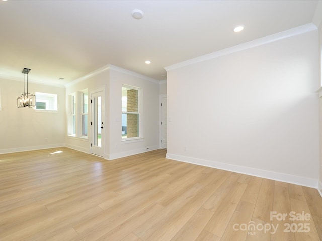unfurnished living room featuring ornamental molding, baseboards, light wood-type flooring, and a chandelier