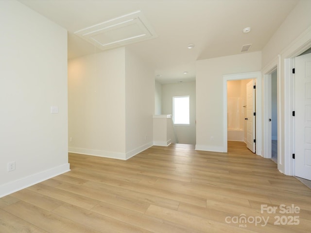 spare room featuring light wood-type flooring, visible vents, recessed lighting, attic access, and baseboards