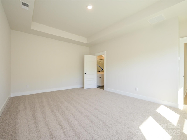 carpeted empty room with a raised ceiling, baseboards, visible vents, and recessed lighting