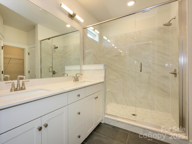 full bathroom featuring a spacious closet, a sink, a shower stall, and double vanity