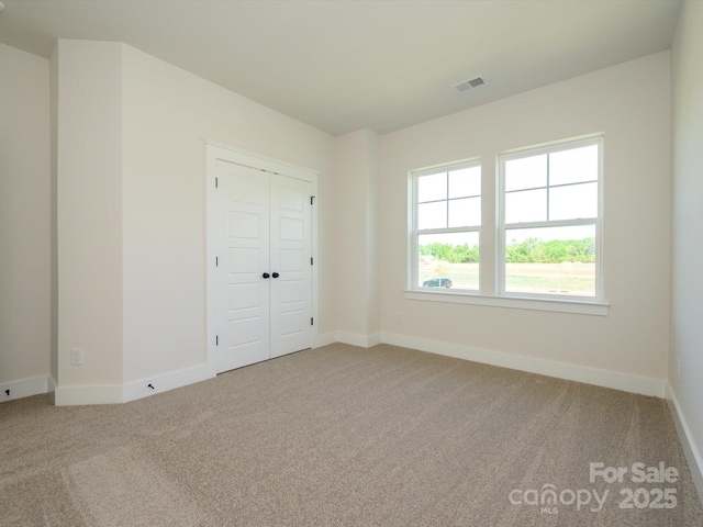 unfurnished bedroom featuring visible vents, baseboards, carpet flooring, and a closet