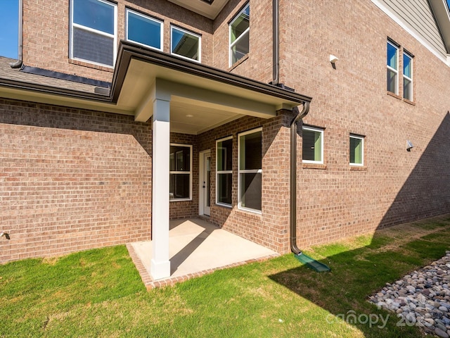 rear view of property with brick siding and a patio
