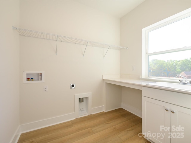 laundry area with hookup for a washing machine, hookup for an electric dryer, cabinet space, light wood-style flooring, and baseboards