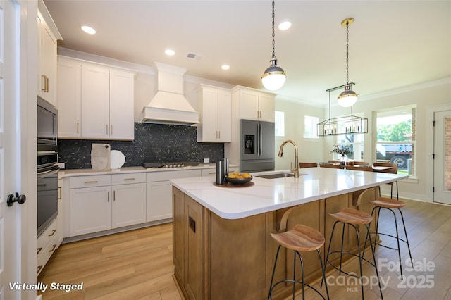17021 Malone Ln, Mint Hill, NC 28227 - kitchen featuring appliances with stainless steel finishes, a sink, premium range hood, light wood-type flooring, and crown molding