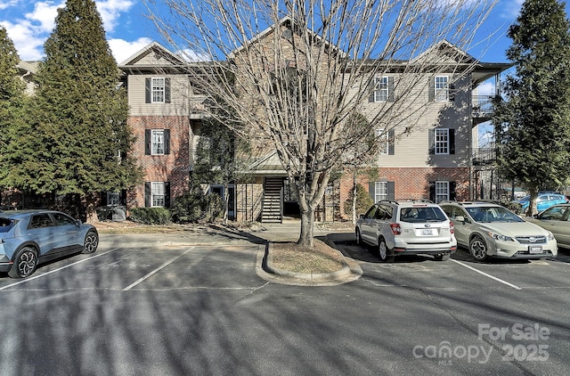 view of property featuring uncovered parking and stairs