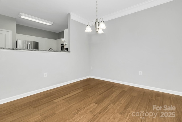 interior space with an inviting chandelier, crown molding, baseboards, and wood finished floors