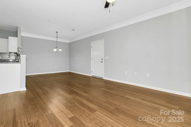 unfurnished living room with baseboards, ornamental molding, wood finished floors, and ceiling fan with notable chandelier