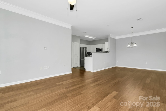 unfurnished living room featuring baseboards, ceiling fan with notable chandelier, wood finished floors, and ornamental molding