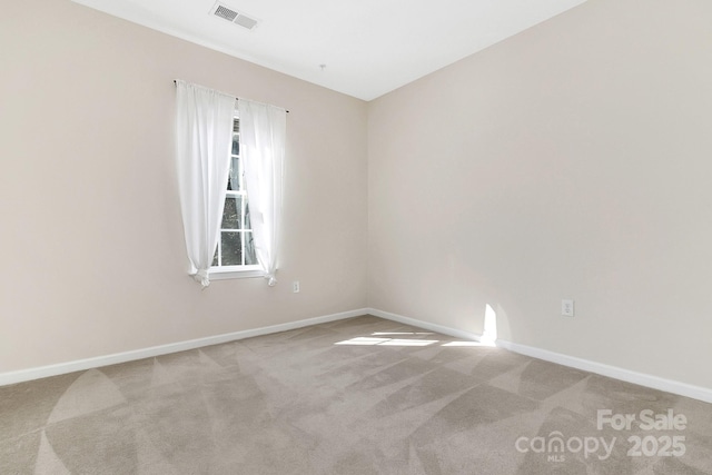 spare room featuring carpet, visible vents, and baseboards