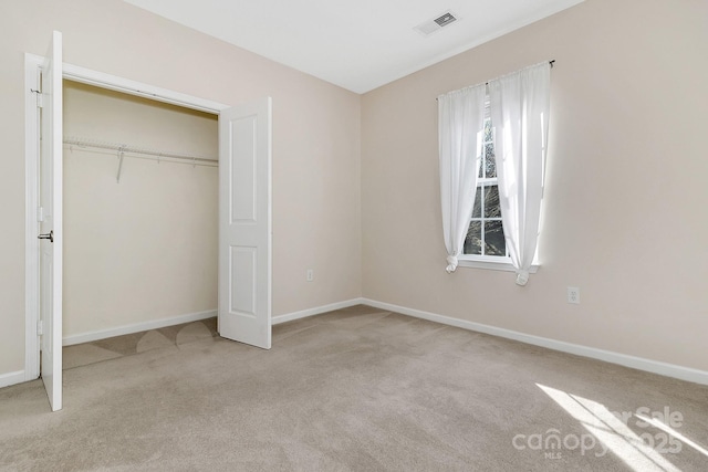 unfurnished bedroom with carpet floors, a closet, visible vents, and baseboards