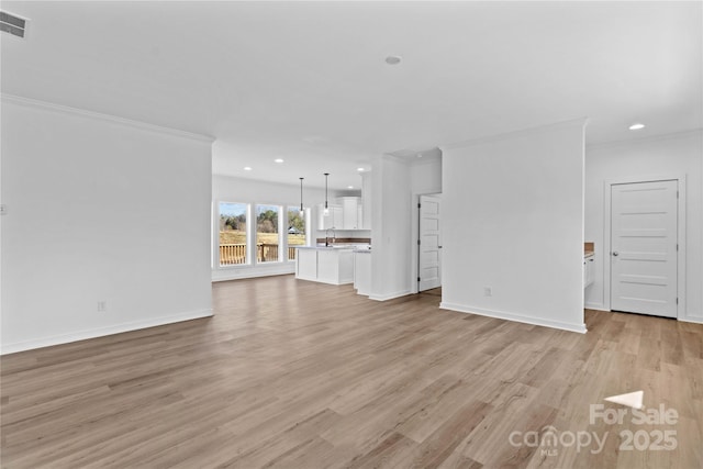 unfurnished living room with light wood-type flooring, sink, and crown molding