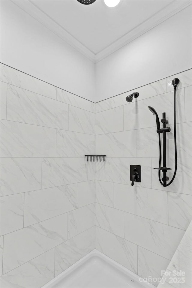 bathroom with tiled shower and crown molding