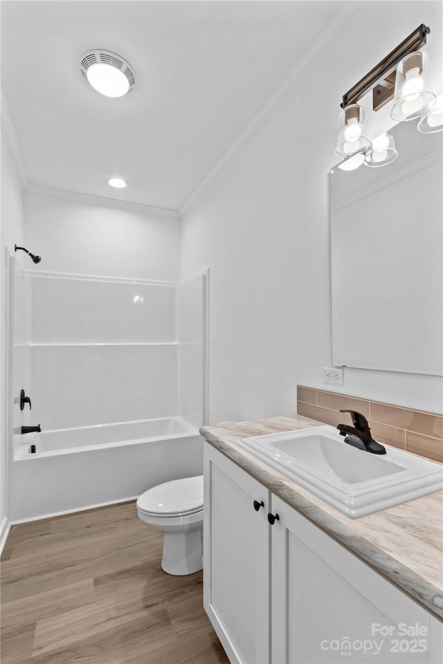 full bathroom featuring hardwood / wood-style flooring, toilet,  shower combination, vanity, and crown molding