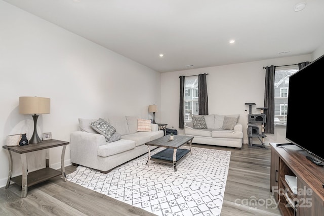 living area with baseboards, wood finished floors, and recessed lighting