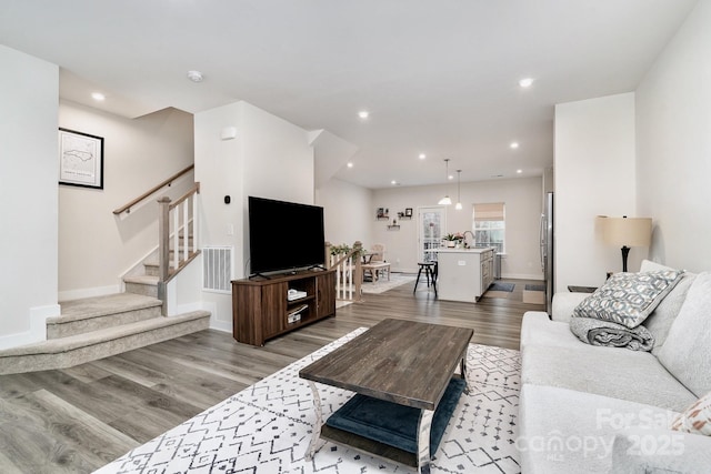 living room featuring recessed lighting, visible vents, stairway, light wood-style floors, and baseboards