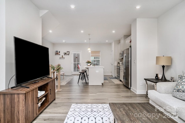 living room with baseboards, recessed lighting, and light wood-style floors