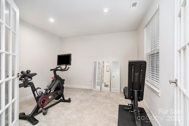 exercise area featuring french doors, light carpet, and baseboards