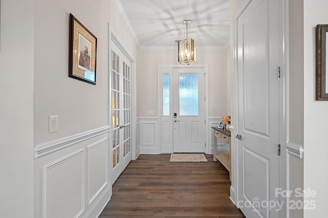 entrance foyer with a chandelier, a decorative wall, dark wood-style flooring, wainscoting, and crown molding