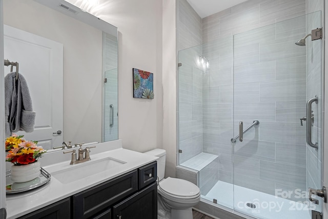 bathroom with toilet, a stall shower, vanity, and visible vents