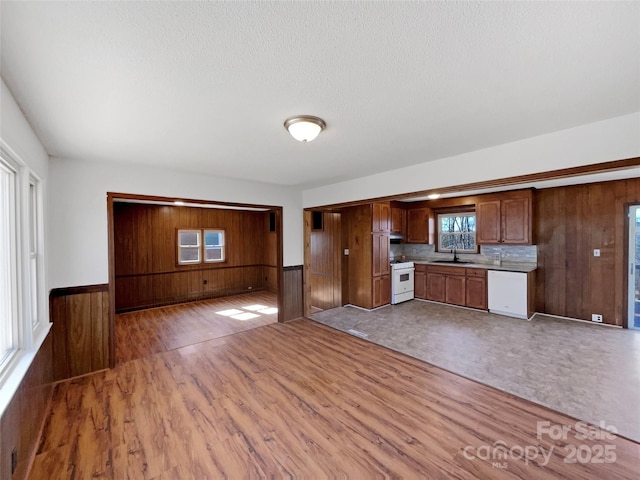 kitchen featuring light countertops, white appliances, wainscoting, and a sink