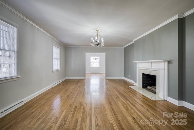 unfurnished living room featuring a chandelier, a premium fireplace, baseboard heating, and wood finished floors