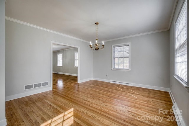 empty room featuring a chandelier, light wood-style flooring, a wealth of natural light, and visible vents