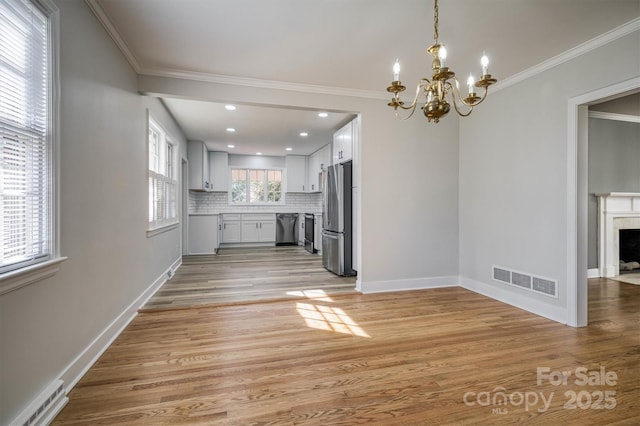 interior space featuring light wood-style flooring, visible vents, stainless steel appliances, and backsplash