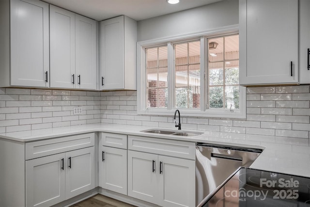 kitchen with dishwasher, tasteful backsplash, light countertops, and a sink