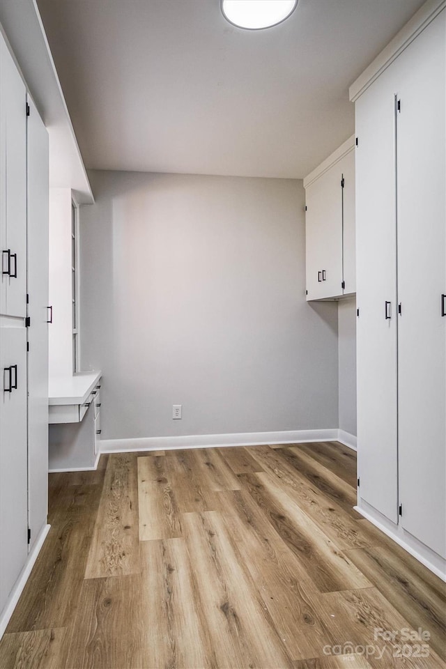 laundry room featuring baseboards and wood finished floors