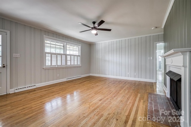 unfurnished living room featuring crown molding, a fireplace, a baseboard heating unit, ceiling fan, and wood finished floors