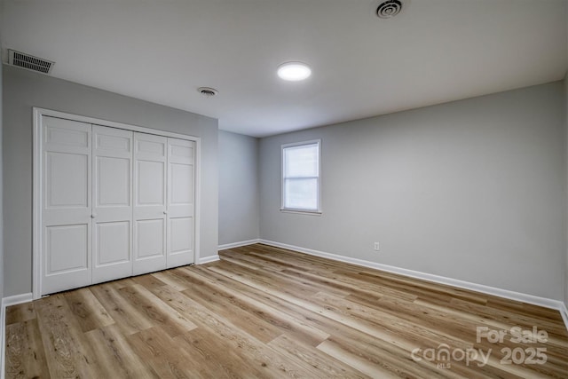 unfurnished bedroom with light wood-style floors, baseboards, visible vents, and a closet