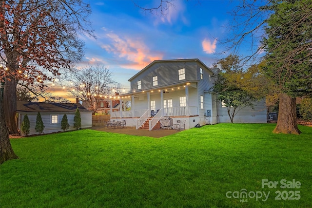 back of house at dusk with an outbuilding, a yard, a porch, and crawl space