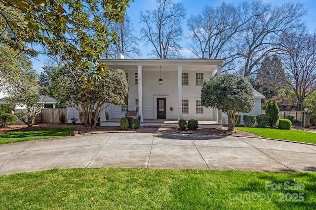 neoclassical / greek revival house featuring a front yard and fence