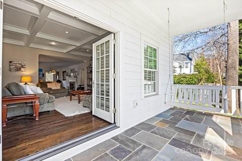 exterior space featuring crown molding, coffered ceiling, beam ceiling, and stone tile floors