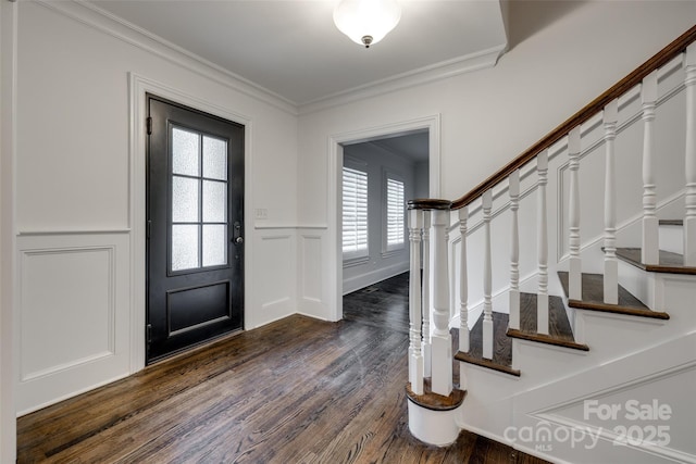 entryway featuring ornamental molding, wainscoting, dark wood finished floors, and a decorative wall