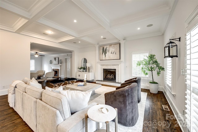 living room with a fireplace with raised hearth, coffered ceiling, and beam ceiling