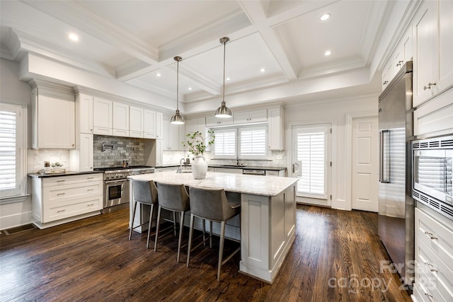 kitchen featuring white cabinets, high end appliances, a kitchen breakfast bar, decorative light fixtures, and a center island