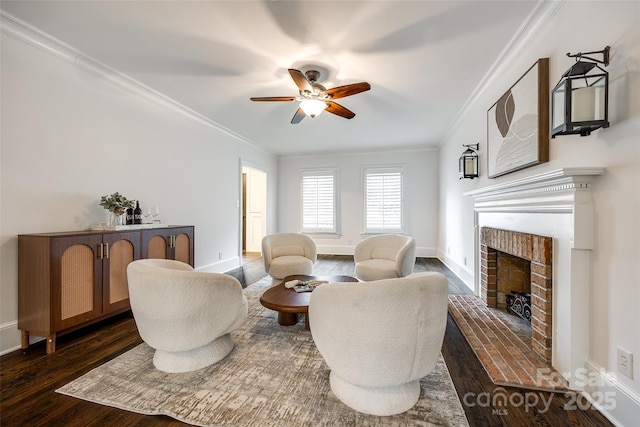 living area featuring dark wood-style flooring, ornamental molding, a ceiling fan, a brick fireplace, and baseboards