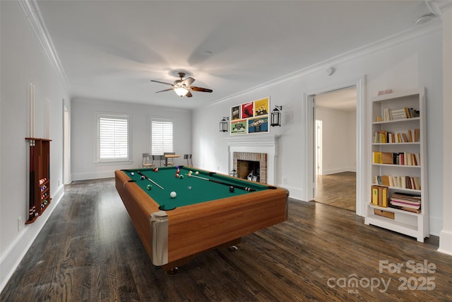 game room with dark wood-style floors, a fireplace, and ornamental molding