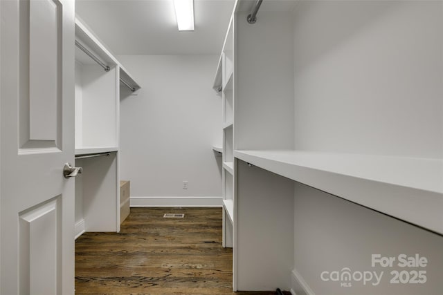 spacious closet with dark wood-style flooring and visible vents