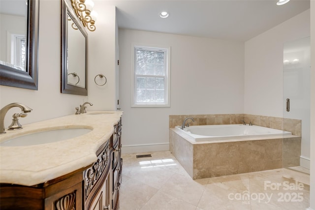 full bathroom with double vanity, a garden tub, baseboards, and a sink