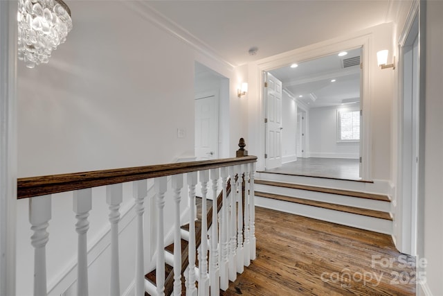 stairway with crown molding, visible vents, wood finished floors, and recessed lighting