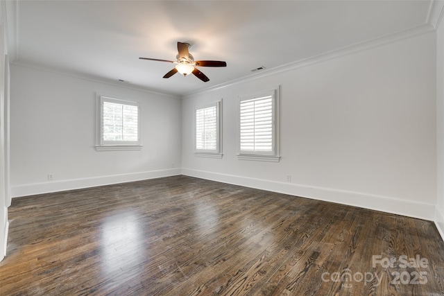 empty room featuring dark wood-style flooring, visible vents, a ceiling fan, baseboards, and ornamental molding