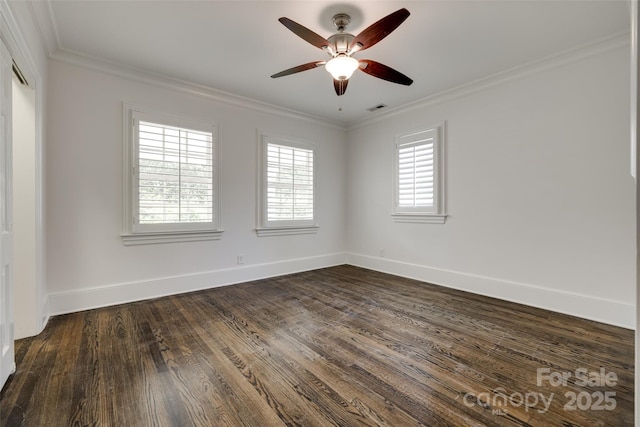 spare room with baseboards, visible vents, dark wood finished floors, and crown molding