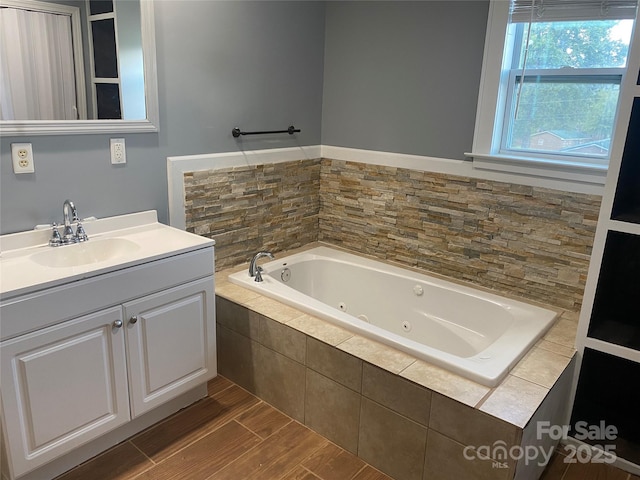 full bath with vanity, a whirlpool tub, and wood finished floors