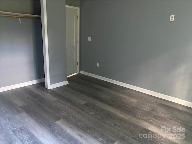 unfurnished bedroom featuring dark wood-style floors, a closet, and baseboards