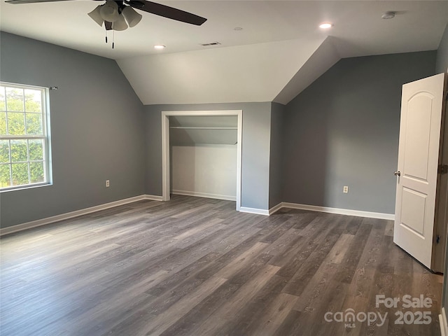 unfurnished bedroom with lofted ceiling, dark wood-type flooring, a closet, and baseboards