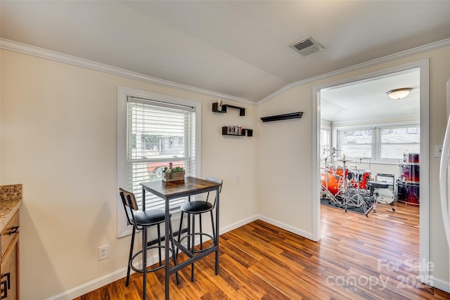 dining room featuring a wealth of natural light, ornamental molding, and wood finished floors