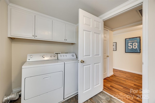 washroom with cabinet space, baseboards, washer and clothes dryer, dark wood-style floors, and ornamental molding