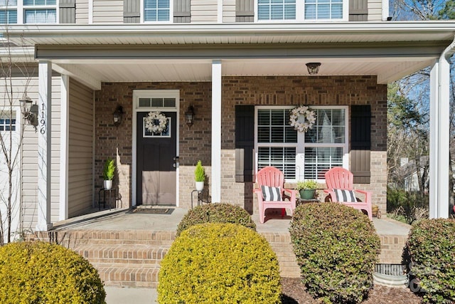 view of exterior entry with covered porch and brick siding